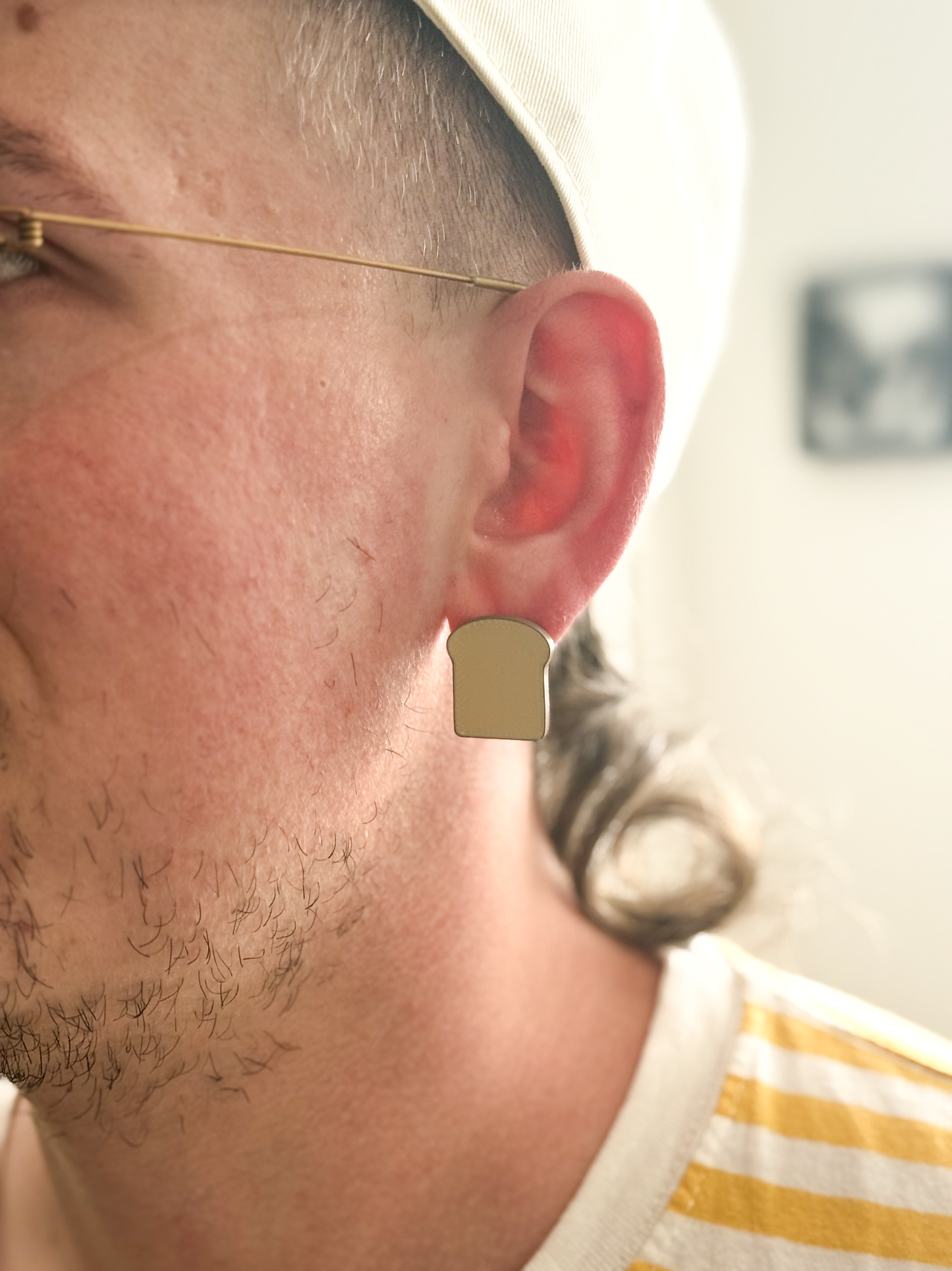 Close-up of a person wearing a Not Made For This Bread earring with a blurred background