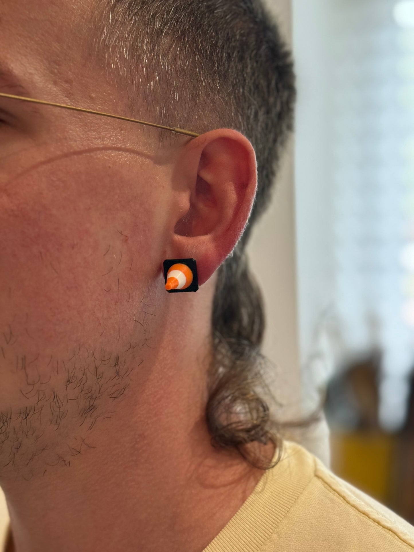 Close-up of a person wearing a Not Made For This cone earring with a blurred background