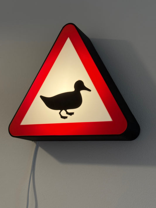 Triangular warning sign with a duck symbol on a gray background made by Not Made For This