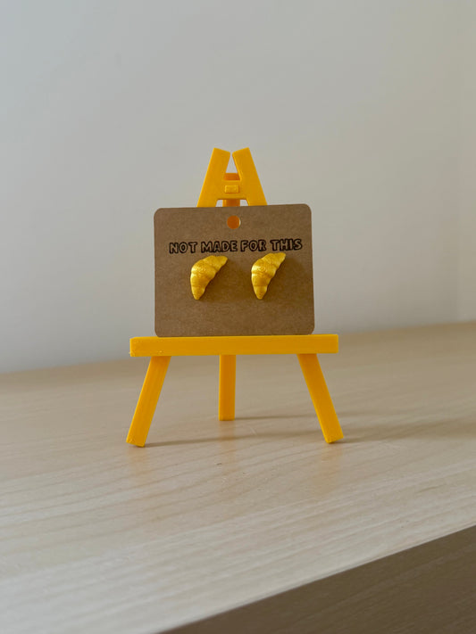 Yellow Not Made For This earrings on a small yellow easel with a brown card displaying text. 